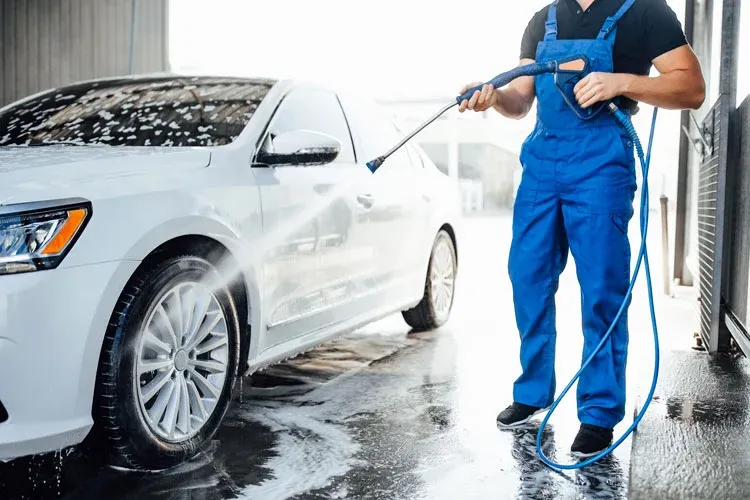 a person in car wash uniform washing car