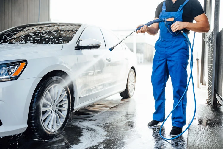 a person in car wash uniform washing car